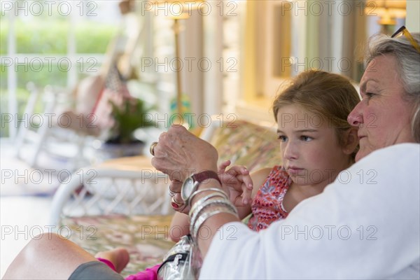 Older Caucasian woman and granddaughter using cell phone together