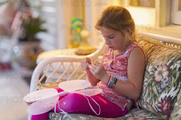 Caucasian girl sewing fairy wings on sofa