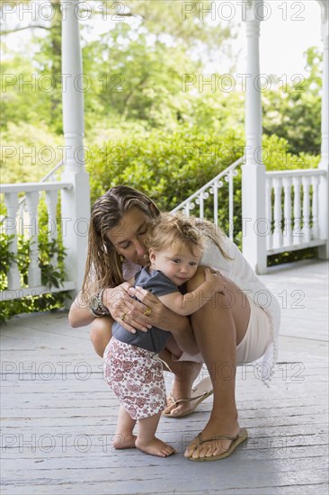 Caucasian mother hugging toddler on porch