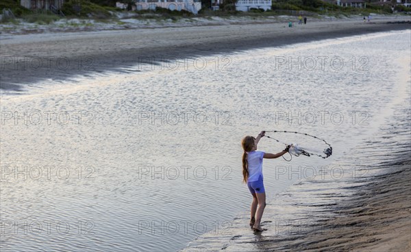 Caucasian girl fishing with net on beach