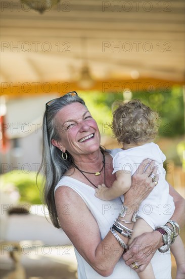 Caucasian older woman holding grandson on porch