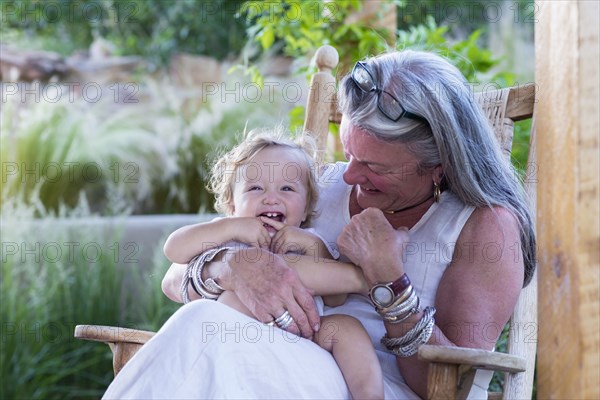 Caucasian older woman holding grandson in rocking chair