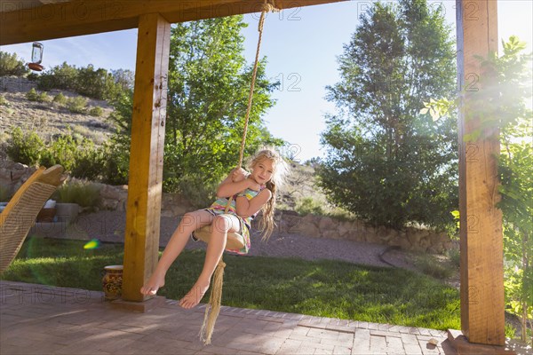 Caucasian girl playing on rope swing