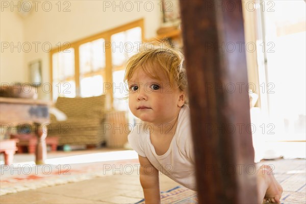 Caucasian toddler crawling on living room floor