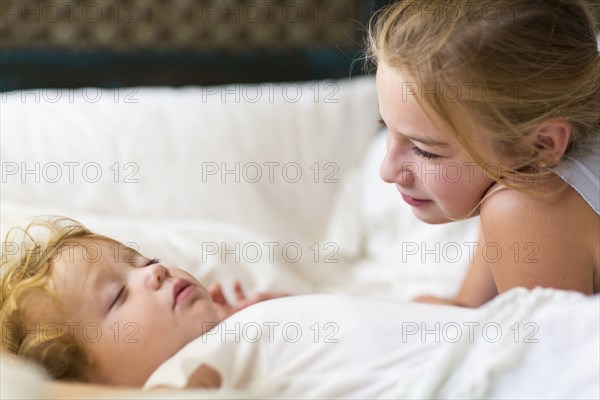 Caucasian girl and toddler brother laying on bed