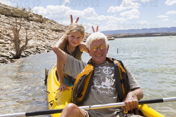 Older Caucasian man posing in kayak with granddaughter