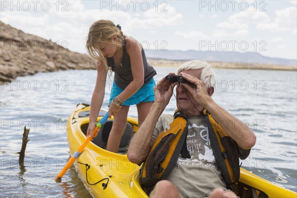 Older Caucasian man in kayak with granddaughter