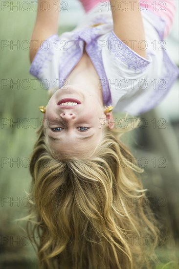 Caucasian girl hanging upside down outdoors