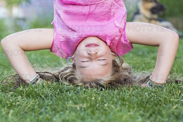 Caucasian girl doing headstand in grass