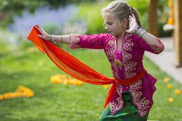 Caucasian girl performing Balinese dance in backyard