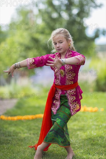 Caucasian girl performing Balinese dance in backyard