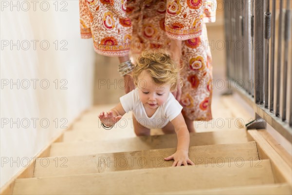 Caucasian mother helping baby son climb stairs