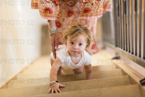 Caucasian mother helping baby son climb stairs