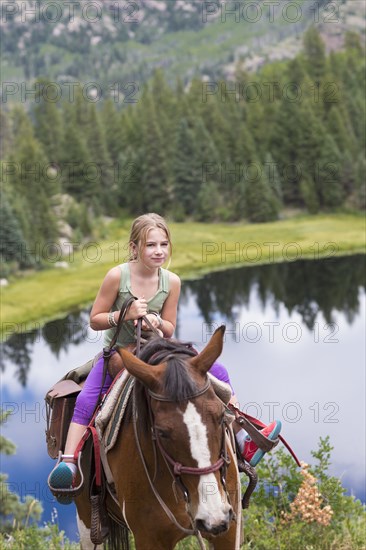 Caucasian girl riding horse in near lake