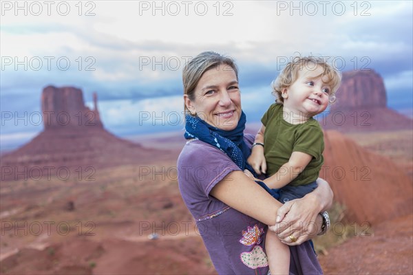 Caucasian mother holding baby son in desert