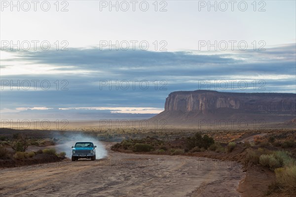 Car driving on dirt road in desert