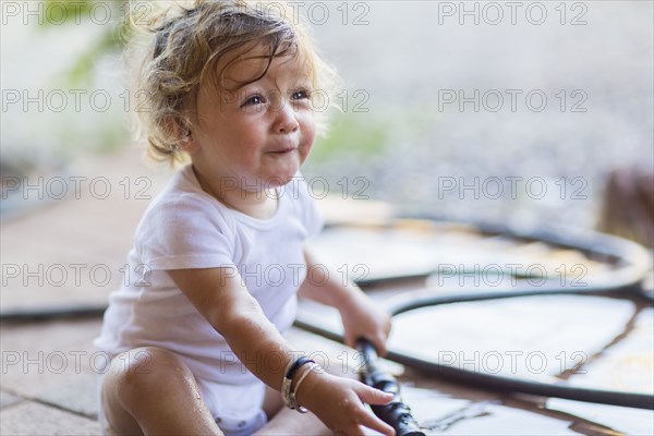 Caucasian toddler boy playing with hose