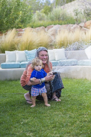 Caucasian grandmother hugging baby grandson in backyard