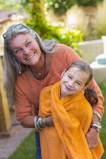 Caucasian grandmother wrapping granddaughter in towel in backyard