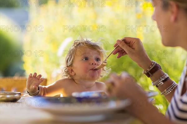 Caucasian mother feeding baby son at table