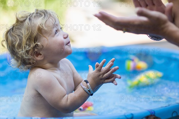 Mother and baby son playing in wading pool