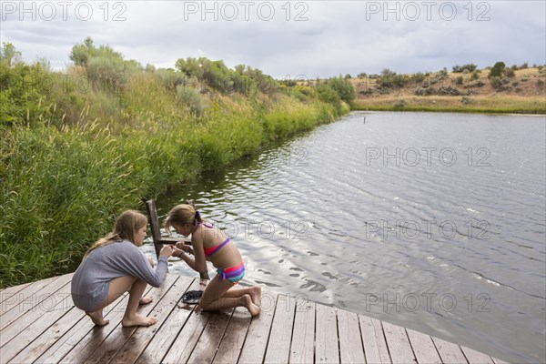Sisters playing together on wooden dock near lake