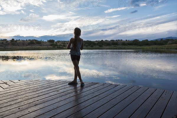 Caucasian girl standing on wooden deck near lake