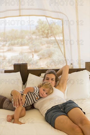 Caucasian mother and baby son relaxing on bed