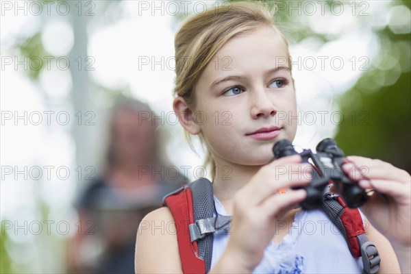 Caucasian girl using binoculars in forest