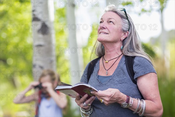 Caucasian senior woman carrying guidebook in forest
