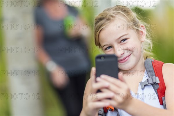 Caucasian girl taking cell phone photograph in forest