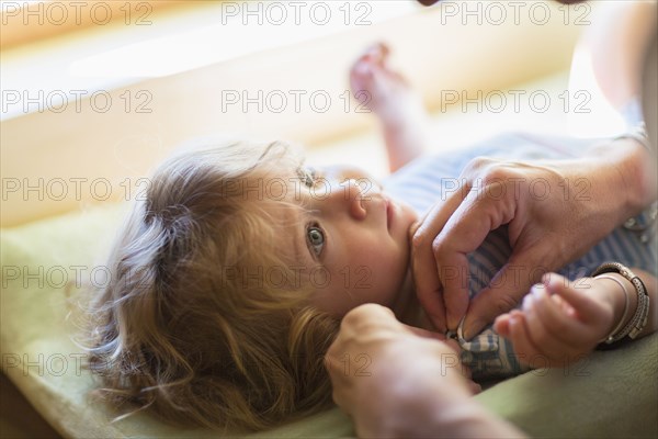 Mother dressing baby boy on changing table