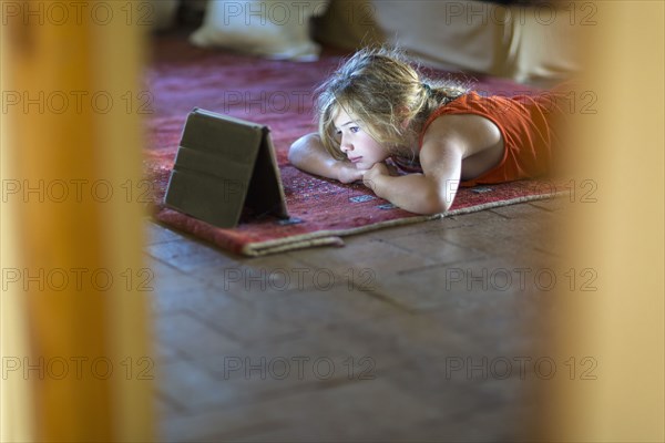 Caucasian girl watching digital tablet on floor