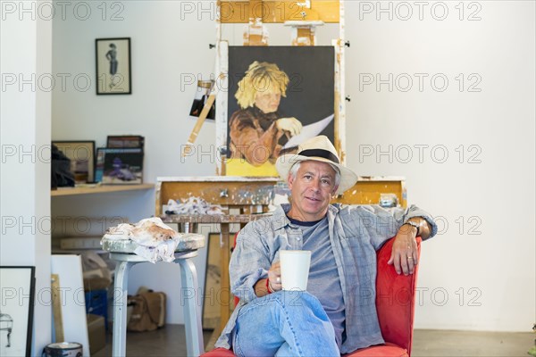 Older Hispanic artist relaxing in studio