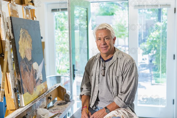 Older Hispanic artist smiling in studio