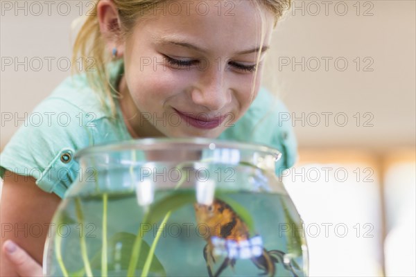 Caucasian girl admiring pet goldfish in fishbowl