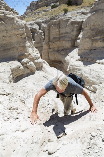 Older Caucasian man climbing rock formations