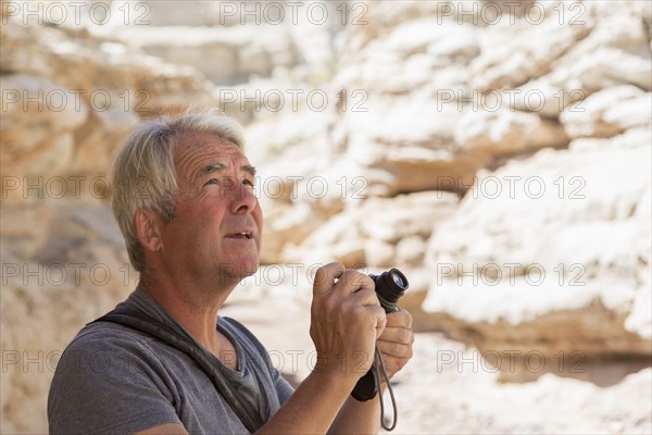 Older Caucasian man photographing rock formations