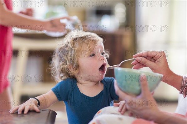 Mother feeding baby son from bowl