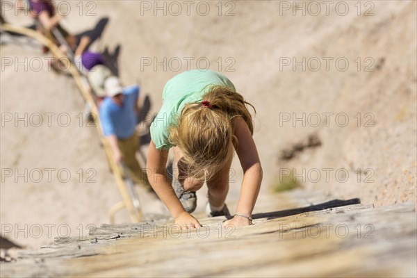 Caucasian girl climbing wooden ladder on hillside