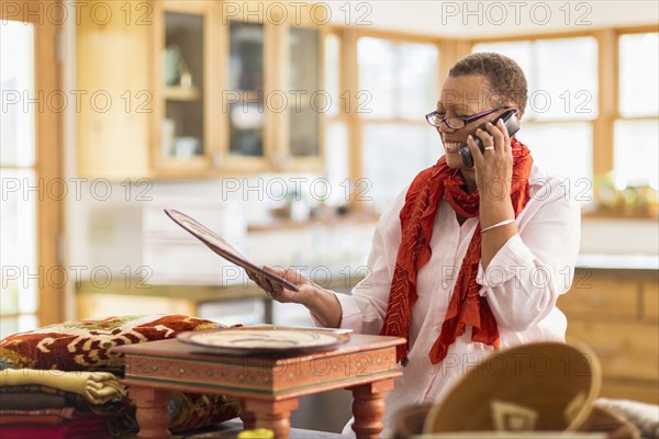 Older mixed race woman talking on telephone in home office