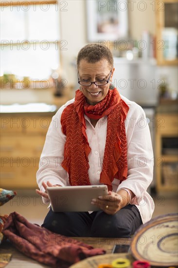 Older mixed race woman using digital tablet in home office