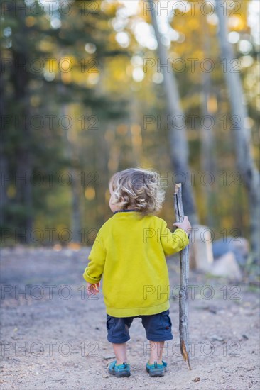 Caucasian boy hiking on dirt path in forest