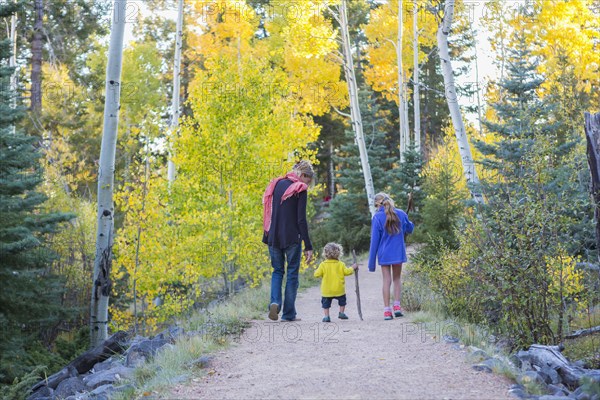 Caucasian mother and children hiking on dirt path in forest