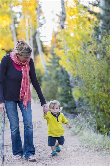 Caucasian mother and son hiking on dirt path in forest