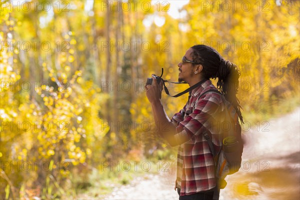 Mixed race hiker taking photograph in forest