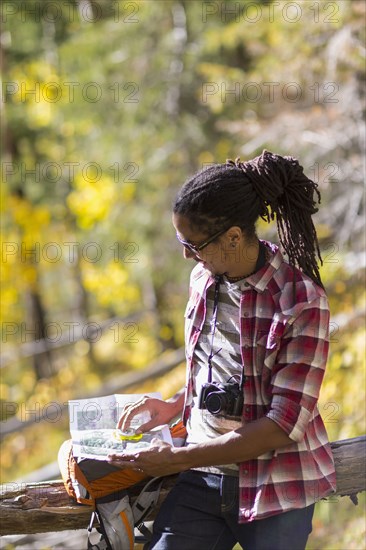 Mixed race hiker reading map in forest