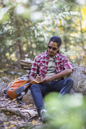 Mixed race hiker writing in forest