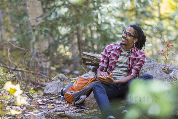 Mixed race hiker writing in forest