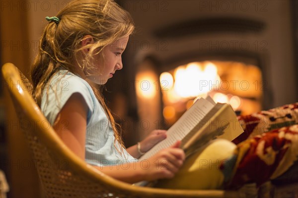 Caucasian girl reading in living room